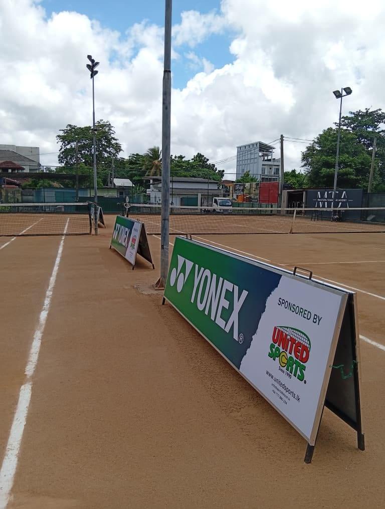 Yonex × United Sports A-frame boards lined up courtside between the courts